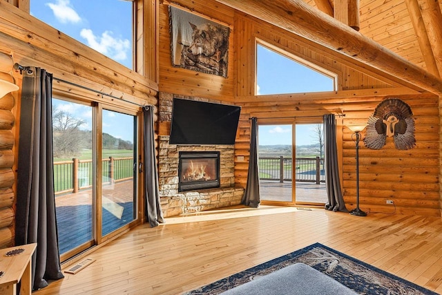 E7498 Mill Rd, Spring Green, WI 53588 - unfurnished living room featuring rustic walls, hardwood / wood-style floors, a fireplace, and a towering ceiling