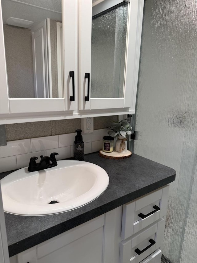 bathroom featuring a shower with shower door, vanity, and tasteful backsplash