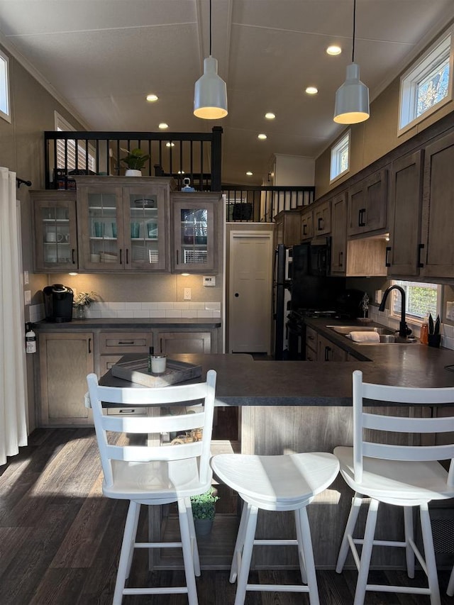 kitchen with pendant lighting, dark brown cabinetry, dark wood-type flooring, and sink