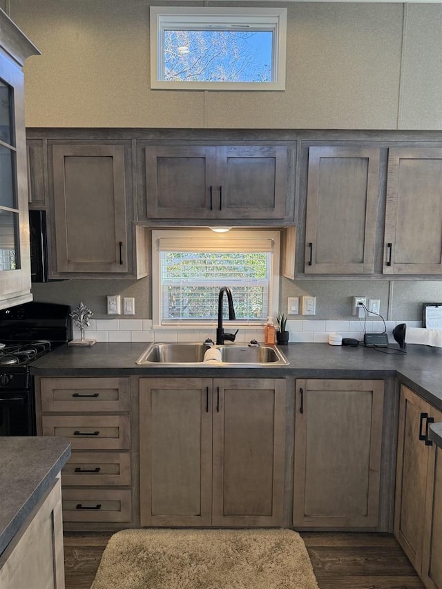 kitchen with dark hardwood / wood-style floors, sink, and black gas range oven