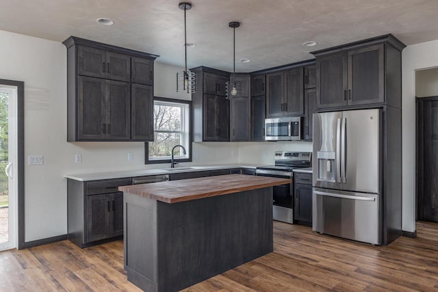 kitchen with stainless steel appliances, sink, dark hardwood / wood-style floors, hanging light fixtures, and a center island