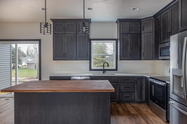 kitchen featuring sink, appliances with stainless steel finishes, wooden counters, a kitchen island, and pendant lighting