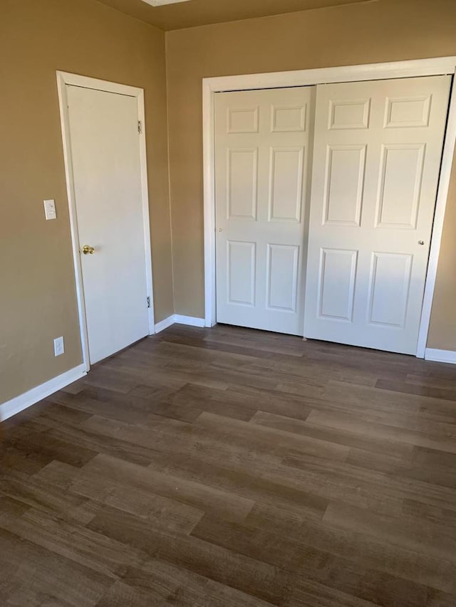 unfurnished bedroom featuring dark wood-type flooring and a closet