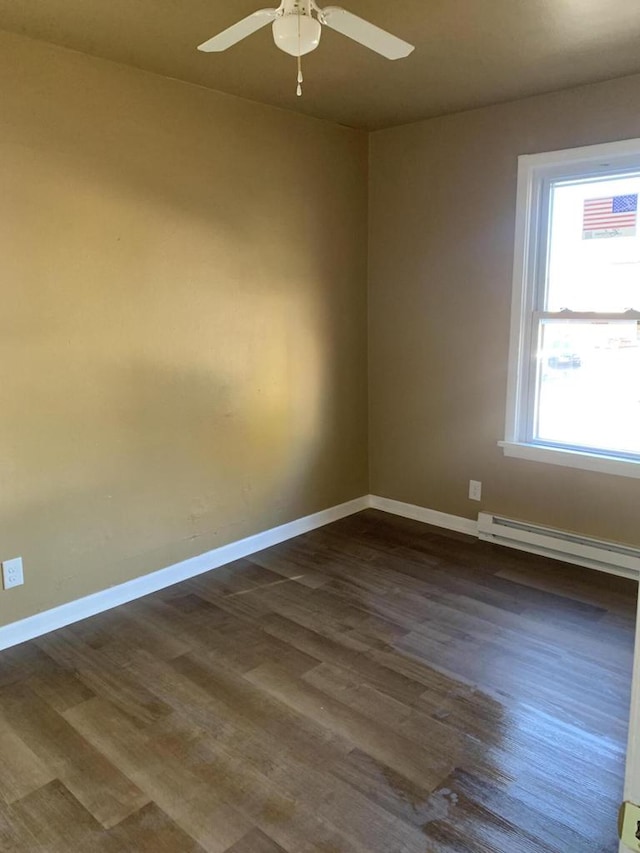 unfurnished room featuring dark hardwood / wood-style flooring, baseboard heating, and ceiling fan