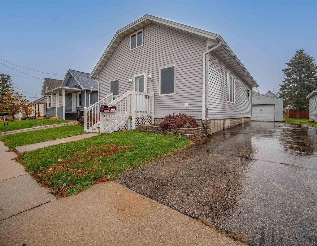 view of front of house featuring a garage, an outdoor structure, and a front lawn