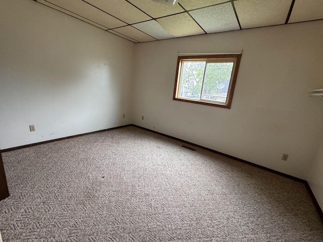 empty room with a drop ceiling and carpet floors