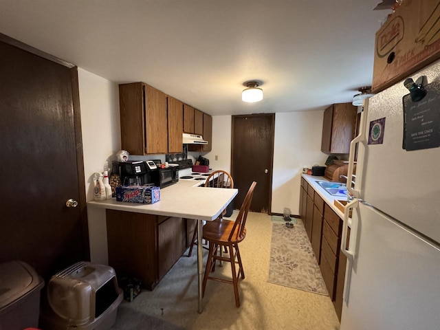 kitchen with a kitchen bar, light colored carpet, kitchen peninsula, sink, and white appliances