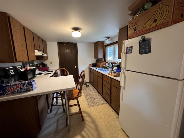 kitchen with white appliances, a breakfast bar area, sink, and kitchen peninsula