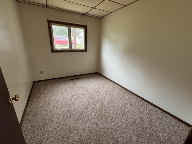 carpeted spare room featuring a paneled ceiling