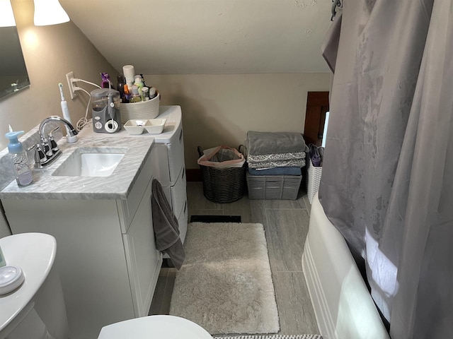 full bathroom featuring separate washer and dryer, shower / tub combo, wood-type flooring, vanity, and toilet