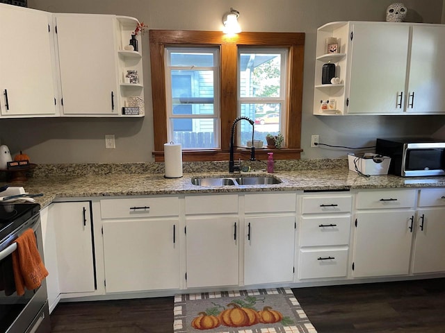 kitchen with light stone counters, white cabinets, sink, dark hardwood / wood-style floors, and appliances with stainless steel finishes