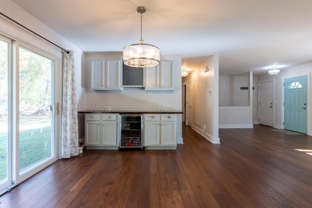 kitchen with dark hardwood / wood-style flooring, pendant lighting, an inviting chandelier, white cabinets, and beverage cooler