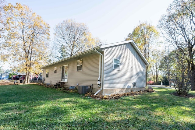 view of side of home with central AC and a yard