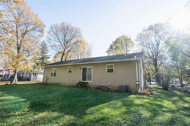 rear view of house featuring central AC unit and a yard