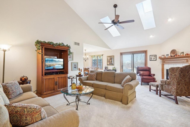 carpeted living room with high vaulted ceiling, a tiled fireplace, and ceiling fan with notable chandelier