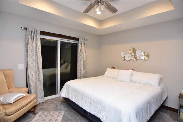 carpeted bedroom featuring a tray ceiling and ceiling fan