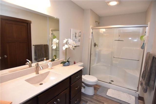 bathroom with hardwood / wood-style floors, an enclosed shower, vanity, and toilet