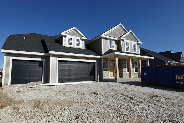1581 Creekview Ln, Oconomowoc, WI 53066 - craftsman-style house featuring covered porch, driveway, a garage, and stone siding