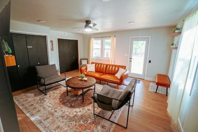 living room with light wood-type flooring and ceiling fan