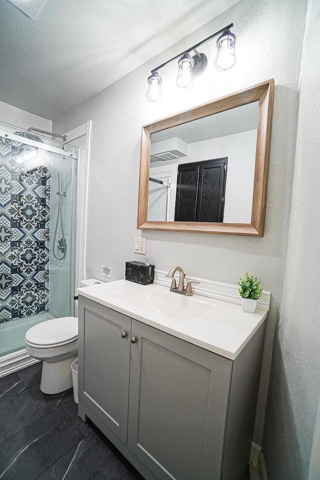 bathroom with a shower with shower door, vanity, toilet, and a textured ceiling