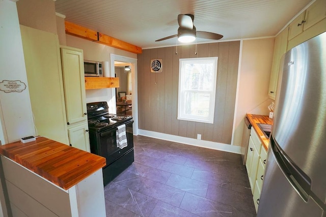 kitchen with butcher block counters, wooden walls, ceiling fan, and stainless steel appliances