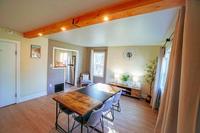 dining area with light wood-type flooring and lofted ceiling with beams