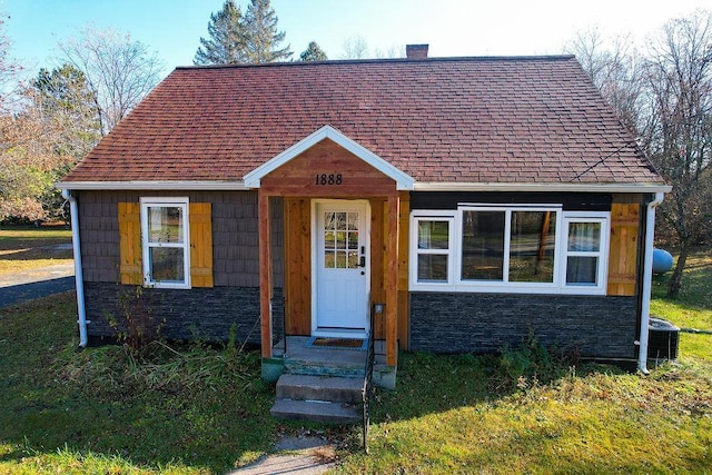 bungalow with central air condition unit and a front yard