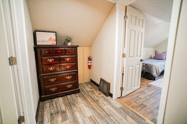 corridor featuring light hardwood / wood-style floors and vaulted ceiling