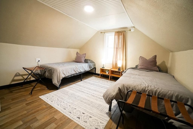 bedroom with hardwood / wood-style floors and lofted ceiling