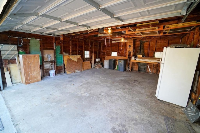 garage with a garage door opener, a workshop area, and white fridge