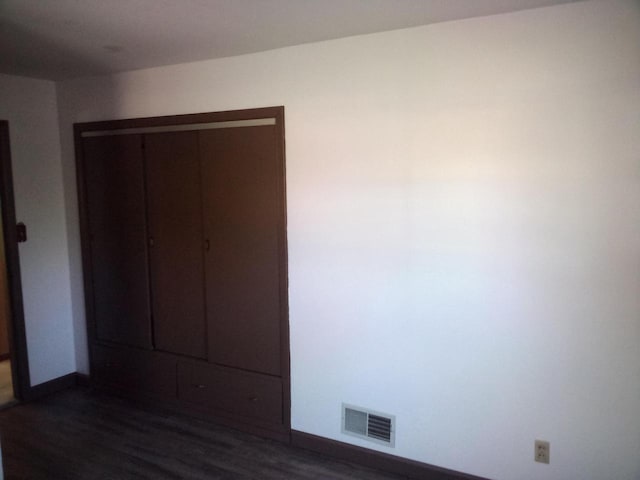 unfurnished bedroom featuring dark hardwood / wood-style flooring and a closet