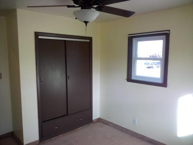 unfurnished bedroom featuring ceiling fan, a closet, and light colored carpet