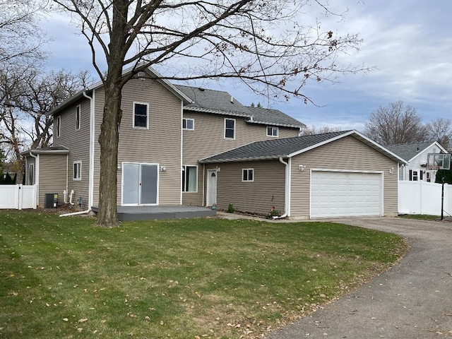 rear view of house with a garage, central AC, and a yard