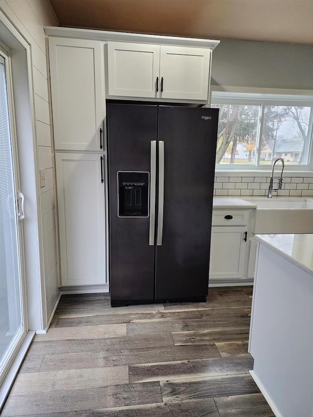 kitchen featuring white cabinetry, hardwood / wood-style floors, refrigerator with ice dispenser, and sink