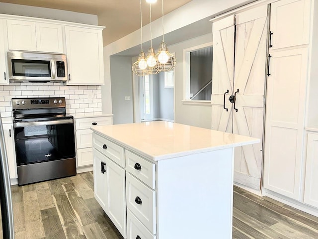 kitchen featuring white cabinetry, appliances with stainless steel finishes, decorative light fixtures, a center island, and light wood-type flooring