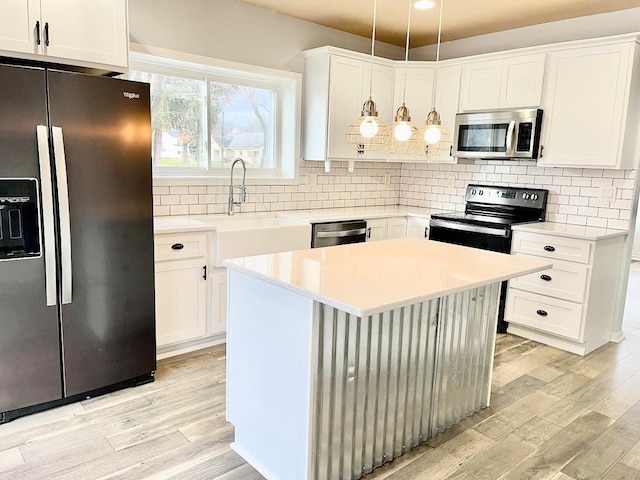 kitchen with pendant lighting, stainless steel appliances, white cabinetry, and light hardwood / wood-style floors