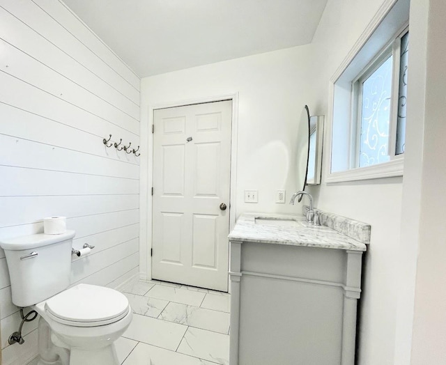 bathroom with vanity, toilet, and wooden walls