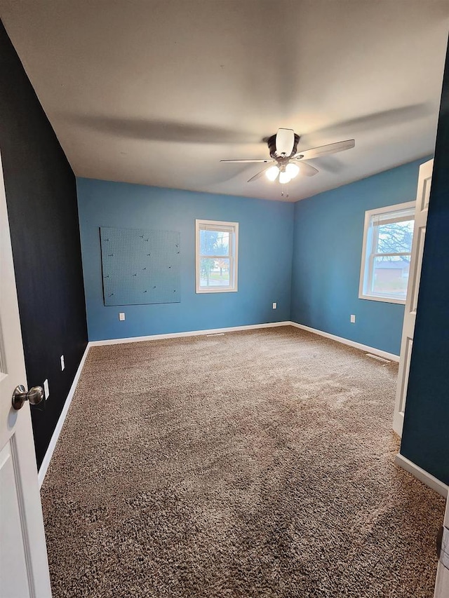 spare room featuring a wealth of natural light, ceiling fan, and carpet flooring