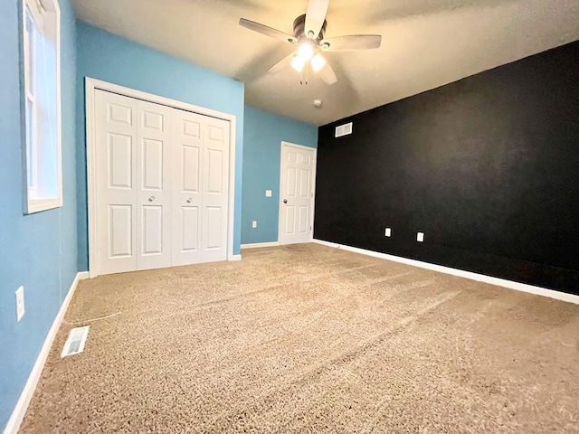 unfurnished bedroom with carpet floors, ceiling fan, and a closet