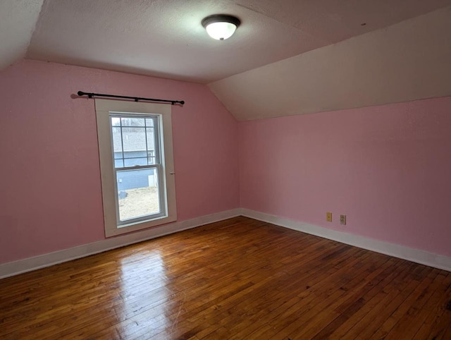 additional living space with wood-type flooring, lofted ceiling, and a textured ceiling