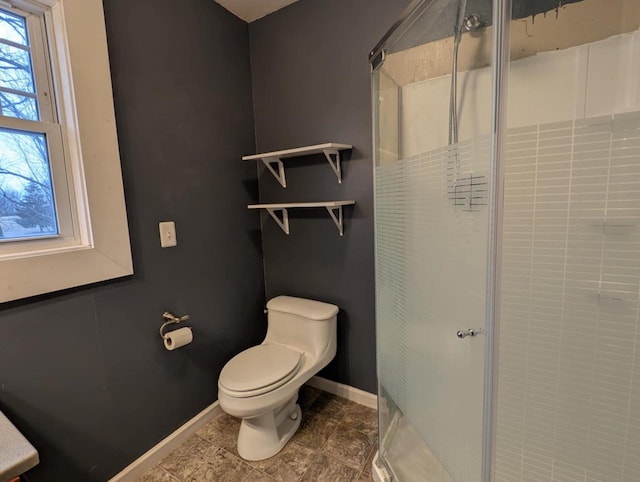 bathroom featuring a shower with shower door and toilet