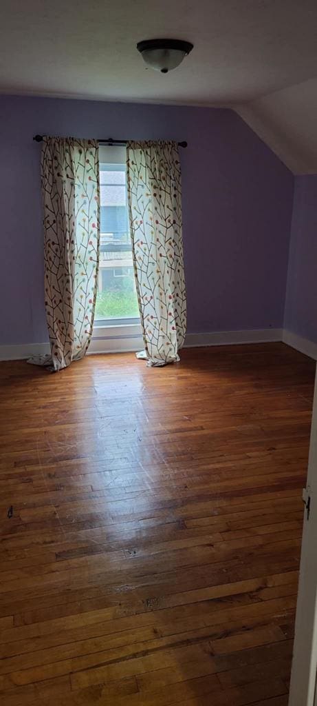 additional living space with dark wood-type flooring and vaulted ceiling