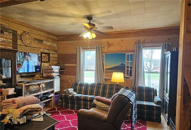 living room with wood walls, wood-type flooring, and ceiling fan