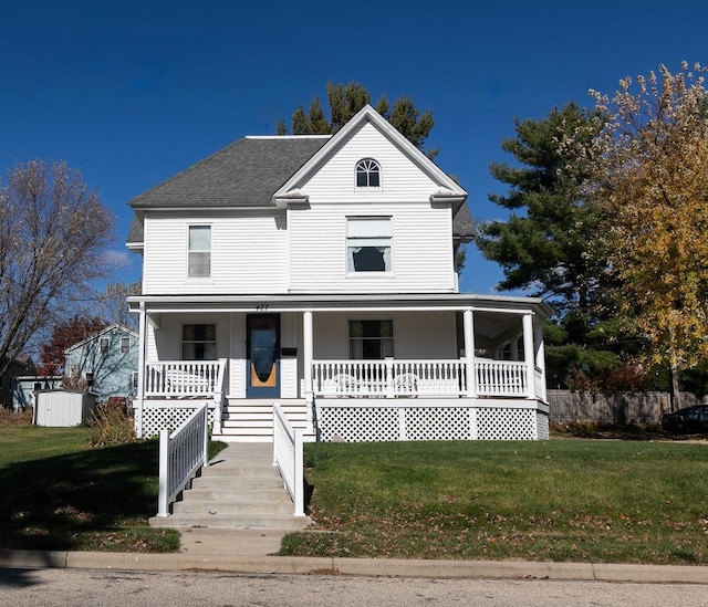 view of front of home with a shed, a front yard, and a porch