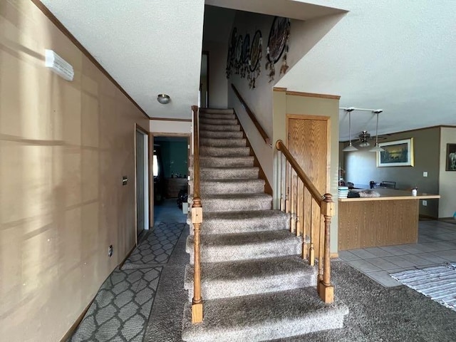 staircase featuring carpet, a textured ceiling, and crown molding