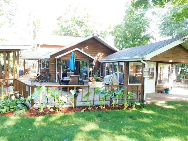 back of house with a deck, a lawn, and a sunroom