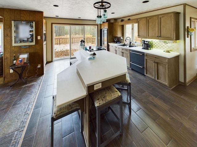 kitchen featuring sink, hanging light fixtures, a chandelier, black electric stovetop, and decorative backsplash