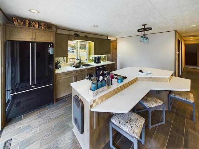 kitchen with black appliances, a kitchen island, sink, decorative backsplash, and a breakfast bar