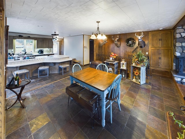 dining area featuring a notable chandelier and wooden walls