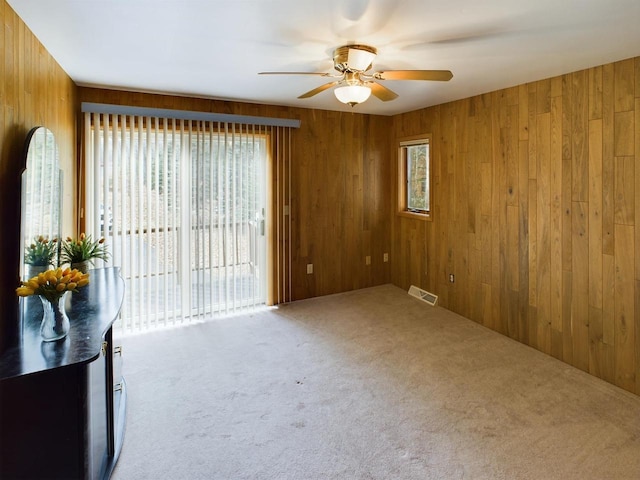 unfurnished room with wooden walls, ceiling fan, and carpet floors